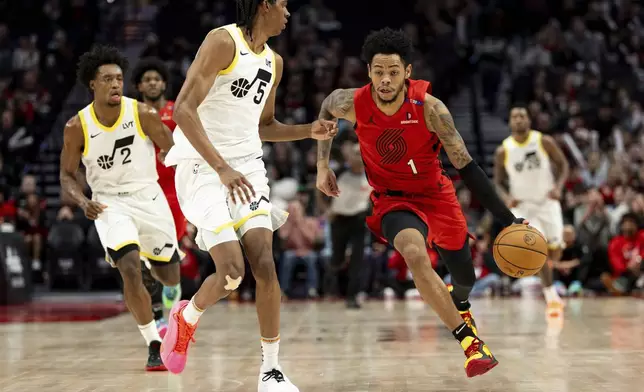 Portland Trail Blazers guard Anfernee Simons, right, dribbles the ball against Utah Jazz forward Cody Williams, left, during the first half of an NBA basketball game, Thursday, Dec. 26, 2024, in Portland, Ore. (AP Photo/Howard Lao)