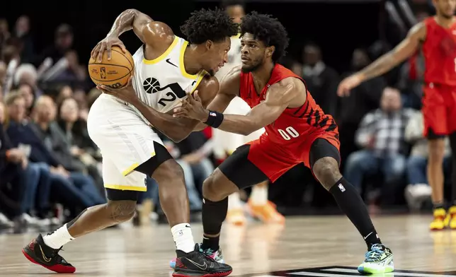 Portland Trail Blazers guard Scoot Henderson, right, guards Utah Jazz guard Collin Sexton during the first half of an NBA basketball game, Thursday, Dec. 26, 2024, in Portland, Ore. (AP Photo/Howard Lao)