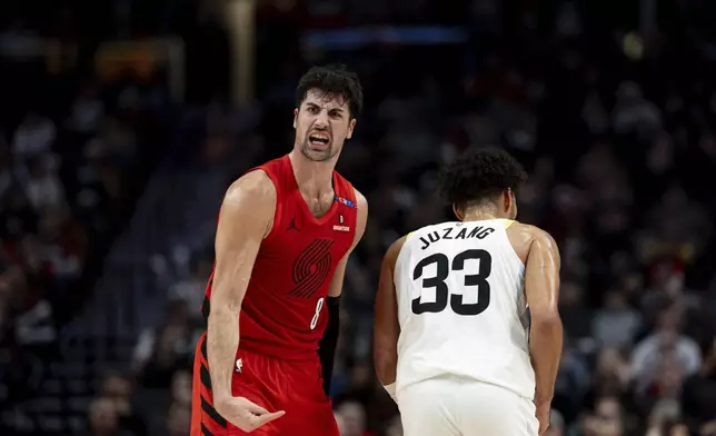 Portland Trail Blazers forward Deni Avdija, left, reacts to Utah Jazz guard Johnny Juzang, right, during the second half of an NBA basketball game Thursday, Dec. 26, 2024, in Portland, Ore. (AP Photo/Howard Lao)