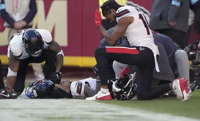 Houston Texans wide receiver Tank Dell is checked on by teammate Jared Wayne, right, after catching a touchdown pass and being injured during the second half of an NFL football game against the Kansas City Chiefs Saturday, Dec. 21, 2024, in Kansas City, Mo. (AP Photo/Charlie Riedel)