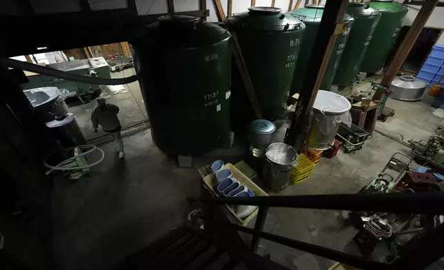 Sake brewer Mie Takahashi walks by tanks used for sake making at her Koten sake brewery in Okaya, central Japan, Saturday, Nov. 30, 2024. (AP Photo/Hiro Komae)