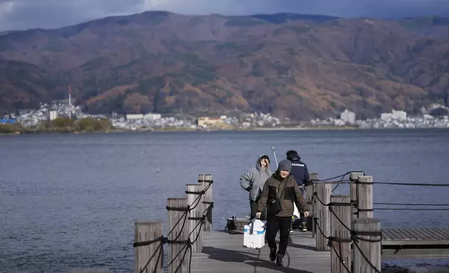 People for smelt fishing at Lake Suwa come back to a pier in Okaya, central Japan, Friday, Nov. 29, 2024. (AP Photo/Hiro Komae)