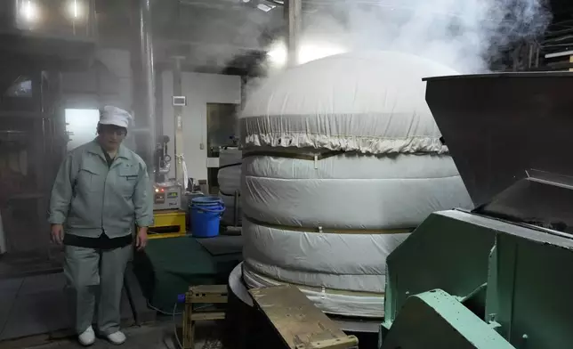 Sake brewer Mie Takahashi walks by a steaming cooker containing about 900 kilograms (2,000 pounds) of rice to be used to make Japanese sake at her Koten sake brewery in Okaya, central Japan, Saturday, Nov. 30, 2024. (AP Photo/Hiro Komae)