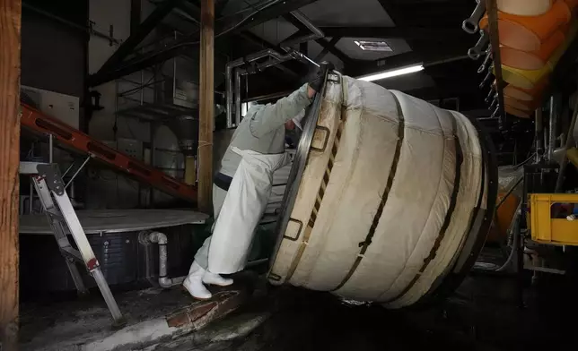 Sake brewer Mie Takahashi moves a big pot that could steam about one ton of rice as she washes it after steaming a batch of it in a sake making process at her Koten sake brewery in Okaya, central Japan, Saturday, Nov. 30, 2024. (AP Photo/Hiro Komae)