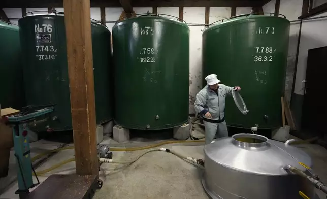 Sake brewer Mie Takahashi checks raw sake after it went through a filtration unit at her Koten sake brewery in Okaya, central Japan, Saturday, Nov. 30, 2024. (AP Photo/Hiro Komae)