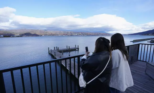 Visitors take photos of Lake Suwa from a cafe in Okaya, central Japan, Friday, Nov. 29, 2024. (AP Photo/Hiro Komae)