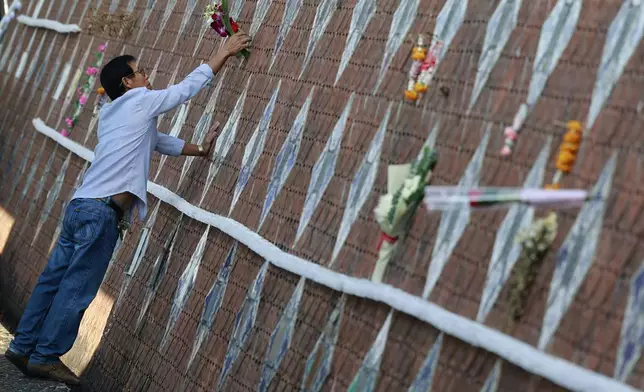 A relative of a victim of a 2004 Indian Ocean tsunami offers flowers during its 20th anniversary at Tsunami Memorial Park at Ban Nam Khem, Takuapa district of Phang Nga province, southern Thailand, Thursday, Dec. 26, 2024. (AP Photo/Wason Wanichakorn)