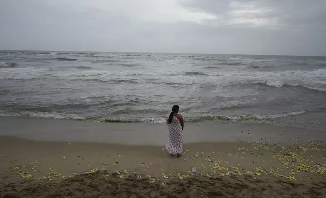 A woman offers tributes in remembrance of victims of the 2004 tsunami on the 20th anniversary of the tragedy, at Marina Beach in Chennai, India, Thursday, Dec. 26, 2024. (AP Photo/Mahesh Kumar A.)