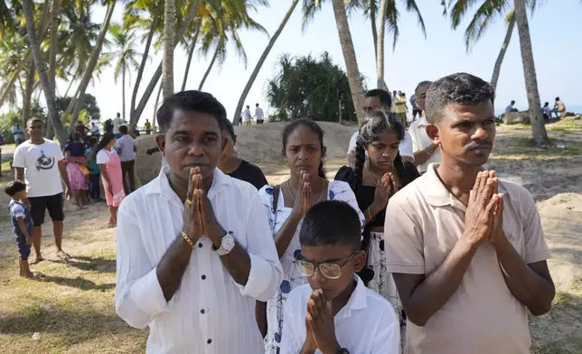 People pray for their dead relatives in the 2004 Indian Ocean tsunami standing by a mass grave during a memorial of 20th anniversary of the calamity in Peraliya, Sri Lanka, Thursday, Dec. 26, 2024. (AP Photo/Eranga Jayawardena)