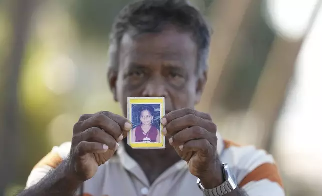 Dayaratne Halambage shows a portrait of his daughter who died during the 2004 Indian Ocean tsunami at a memorial of the 20th anniversary of the calamity in Peraliya, Sri Lanka, Thursday, Dec. 26, 2024. (AP Photo/Eranga Jayawardena)