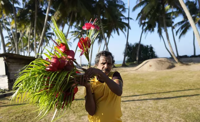 A man carries flowers to offer at a memorial built in memory of those who died during 2004 Indian Ocean tsunami, on the 20th anniversary of the calamity in Peraliya, Sri Lanka, Thursday, Dec. 26, 2024. (AP Photo/Eranga Jayawardena)