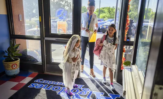 Attendance Clerk Katrice Grant follows siblings Melanie Pacheco, 8, right and Marilynn Pacheco, 5, as they arrive for school, Tuesday, Oct. 1, 2024, at Algodones Elementary School in Algodones, N.M. (AP Photo/Roberto E. Rosales)