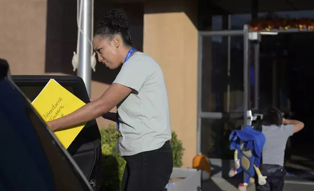 Attendance Clerk Katrice Grant looks to help a student get out a a car as he is dropped off at school, Tuesday, Oct. 1, 2024, at Algodones Elementary School in Algodones, N.M. (AP Photo/Roberto E. Rosales)