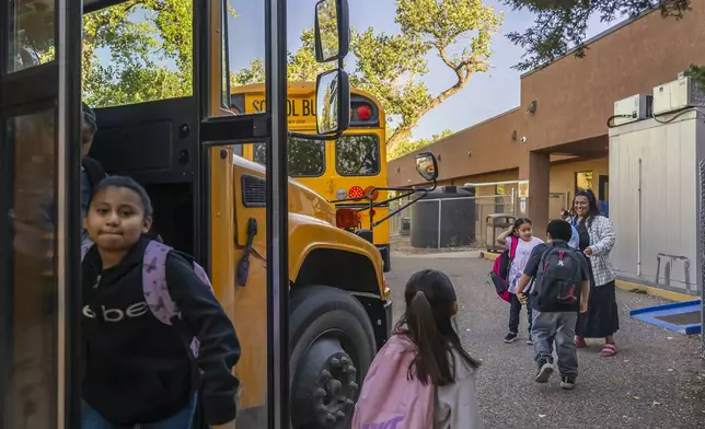 Social worker Mary Schmauss, rear right, greets students as they arrive for school, Tuesday, Oct. 1, 2024, at Algodones Elementary School in Algodones, N.M. (AP Photo/Roberto E. Rosales)