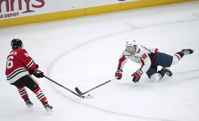 Chicago Blackhawks' Teuvo Teravainen (86) grabs the puck from a diving Washington Capitals' Andrew Mangiapane during the first period of an NHL hockey game Tuesday, Dec. 17, 2024, in Chicago. (AP Photo/Charles Rex Arbogast)