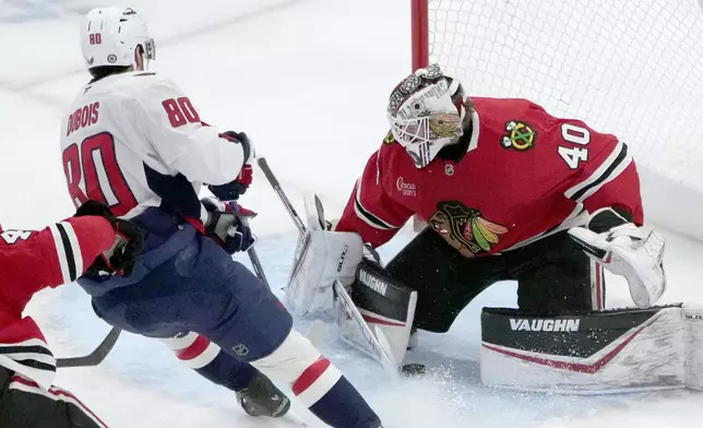 Washington Capitals' Pierre-Luc Dubois scores between the legs of Chicago Blackhawks goaltender Arvid Soderblom during the first period of an NHL hockey game Tuesday, Dec. 17, 2024, in Chicago. (AP Photo/Charles Rex Arbogast)