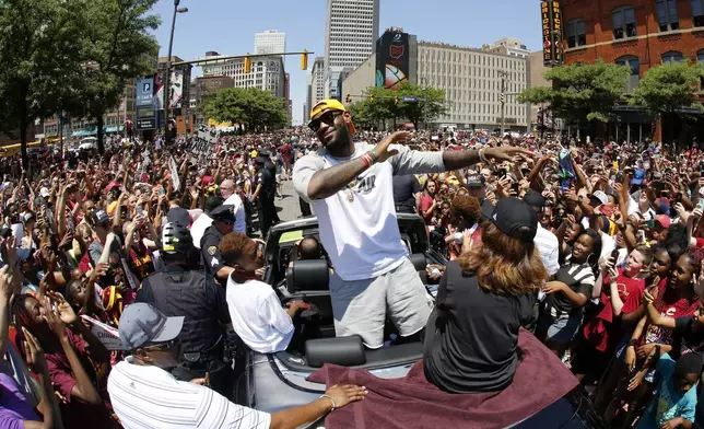 FILE - Cleveland Cavaliers' LeBron James, center, stands in the back of a Rolls Royce as it makes its way through the crowd lining the parade route in downtown Cleveland, on June 22, 2016, celebrating the basketball team's NBA championship. (AP Photo/Gene J. Puskar, File)