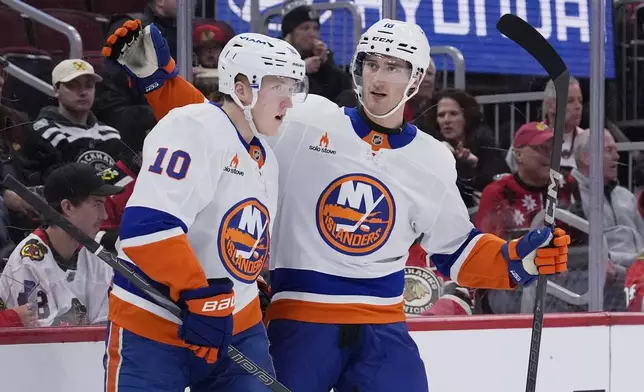 New York Islanders right wing Simon Holmstrom, left, is congratulated by left wing Pierre Engvall, right, after scoring during the second period of an NHL hockey game against the Chicago Blackhawks in Chicago, Sunday, Dec. 15, 2024. (AP Photo/Nam Y. Huh)