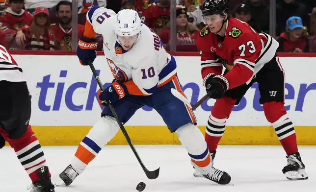 New York Islanders right wing Simon Holmstrom (10) controls the puck against Chicago Blackhawks left wing Lukas Reichel, right, during the second period of an NHL hockey game in Chicago, Sunday, Dec. 15, 2024. (AP Photo/Nam Y. Huh)