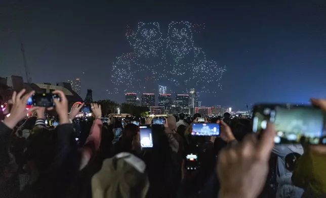 People watch the panda-themed drone show at the waterfront of the Victoria Harbour in Hong Kong, Saturday, Dec. 28, 2024. (AP Photo/Chan Long Hei)