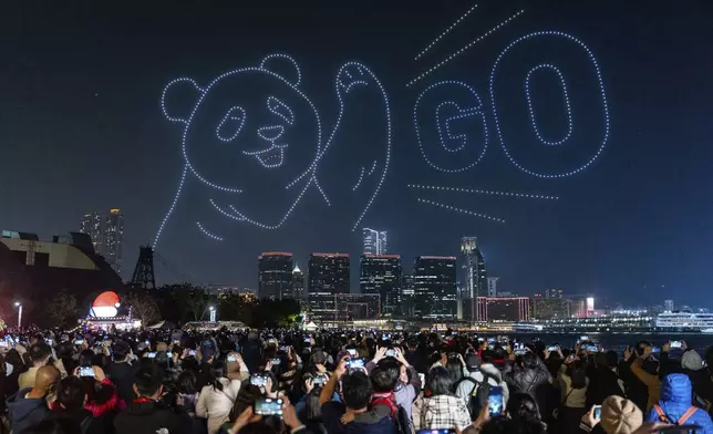 People watch the panda-themed drone show at the waterfront of the Victoria Harbour in Hong Kong, Saturday, Dec. 28, 2024. (AP Photo/Chan Long Hei)