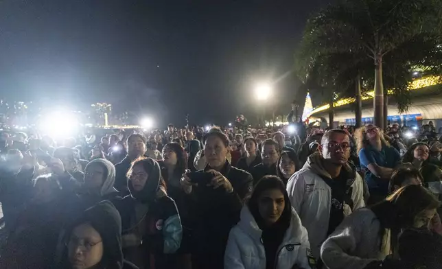 People watch the panda-themed drone show at the waterfront of the Victoria Harbour in Hong Kong, Saturday, Dec. 28, 2024. (AP Photo/Chan Long Hei)