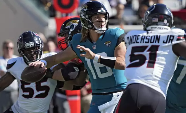 Jacksonville Jaguars quarterback Trevor Lawrence (16) throws a pass while he is pressured by Houston Texans defensive end Danielle Hunter (55) and defensive end Will Anderson Jr. (51) during the first half of an NFL football game Sunday, Dec. 1, 2024, in Jacksonville, Fla. (AP Photo/John Raoux)