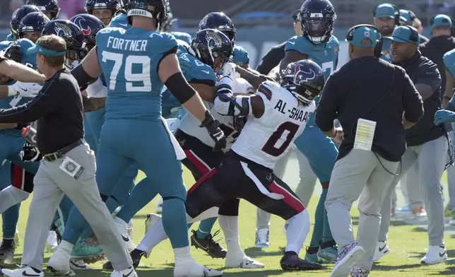 Players fight after Houston Texans linebacker Azeez Al-Shaair (0) hit Jacksonville Jaguars quarterback Trevor Lawrence with a late hit during the first half of an NFL football game Sunday, Dec. 1, 2024, in Jacksonville, Fla. (AP Photo/John Raoux)