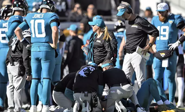 Jacksonville Jaguars head coach Doug Pederson, second from right, looks on a trainers attend to quarterback Trevor Lawrence after a late hit by Houston Texans linebacker Azeez Al-Shaair during the first half of an NFL football game Sunday, Dec. 1, 2024, in Jacksonville, Fla. (AP Photo/Phelan M. Ebenhack)