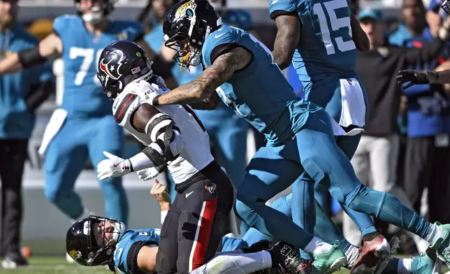 Jacksonville Jaguars tight end Evan Engram (17, right) jumps on Houston Texans linebacker Azeez Al-Shaair (0) after his late hit on quarterback Trevor Lawrence (16) during the first half of an NFL football game Sunday, Dec. 1, 2024, in Jacksonville, Fla. (AP Photo/Phelan M. Ebenhack)