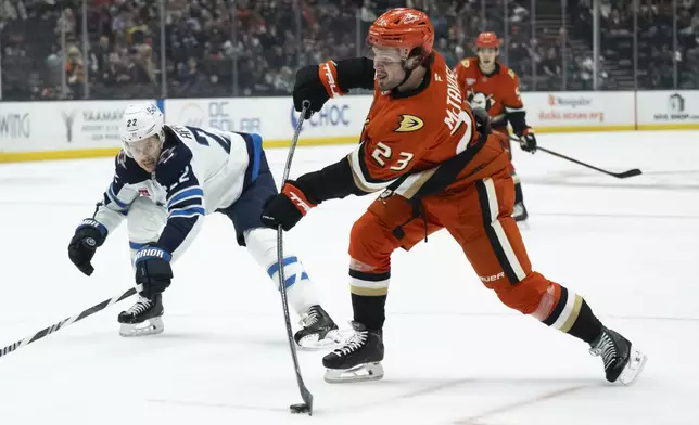 Anaheim Ducks center Mason McTavish (23) shoots past Winnipeg Jets center Mason Appleton (22) during the first period of an NHL hockey game, Wednesday, Dec. 18, 2024, in Anaheim, Calif. (AP Photo/Kyusung Gong)