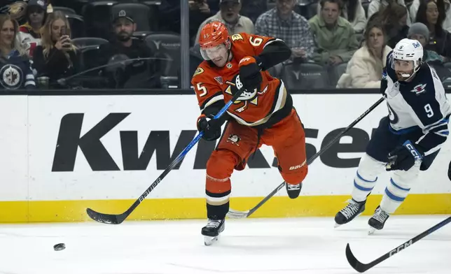 Anaheim Ducks defenseman Jacob Trouba (65) shoots past Winnipeg Jets left wing Alex Iafallo (9) during the first period of an NHL hockey game, Wednesday, Dec. 18, 2024, in Anaheim, Calif. (AP Photo/Kyusung Gong)