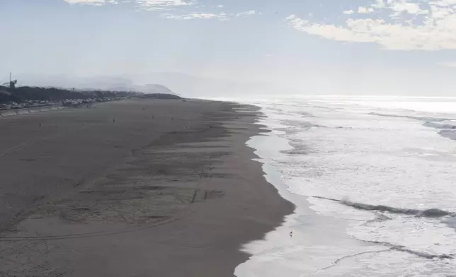 People walk along the sand at Ocean Beach in San Francisco during a tsunami warning on Thursday, Dec. 5, 2024. (AP Photo/Emily Steinberger)