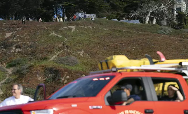 The Fire Department patrols at Ocean Beach in San Francisco while people watch the waves on higher ground during a tsunami warning on Thursday, Dec. 5, 2024. (AP Photo/Emily Steinberger)