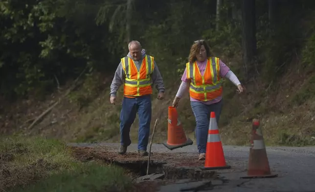 Humboldt County road maintenance workers Wayne Tomasini, left, and Monica Willburn prepare to fill cracks with dirt on a road damaged by a 7.0 earthquake in Humboldt County, Calif., Friday, Dec. 6, 2024. (AP Photo/Godofredo A. Vásquez)