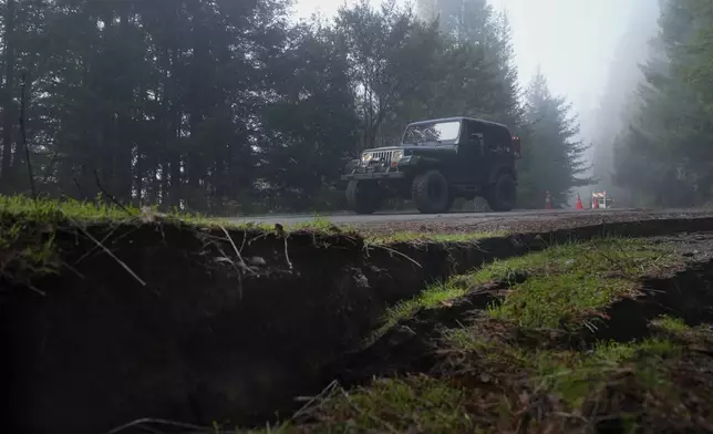 A motorist drives along a road damaged by a 7.0 earthquake Friday, Dec. 6, 2024, in Humboldt County, Calif. (AP Photo/Godofredo A. Vásquez)