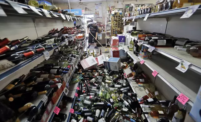 FILE - Bottles of wine are strewn in the middle of an aisle as Victor Abdullatif, background center, mops inside of the Eastridge Market, his family's store, on July 6, 2019, in Ridgecrest, Calif., after an earthquake jolted the region from Sacramento to Las Vegas to Mexico. (AP Photo/Marcio Jose Sanchez, File)