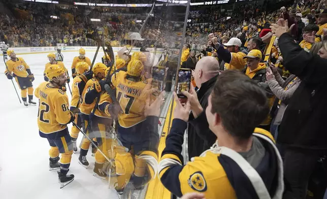 Nashville Predators players celebrate the team's 3-2 overtime win in an NHL hockey game against the Los Angeles Kings, Saturday, Dec. 21, 2024, in Nashville, Tenn. (AP Photo/George Walker IV)