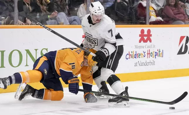 Los Angeles Kings defenseman Kyle Burroughs (7) pushes Nashville Predators center Gustav Nyquist (14) to the ice during the second period of an NHL hockey game Saturday, Dec. 21, 2024, in Nashville, Tenn. (AP Photo/George Walker IV)