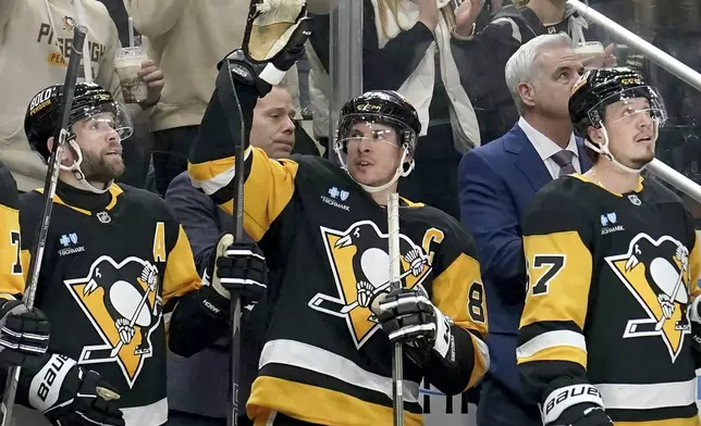 Pittsburgh Penguins' Sidney Crosby, center, acknowledges the crowd after surpassing Mario Lemieux for the franchise record for most assists during the second period of an NHL hockey game against the New York Islanders, Sunday, Dec. 29, 2024, in Pittsburgh. (AP Photo/Matt Freed)