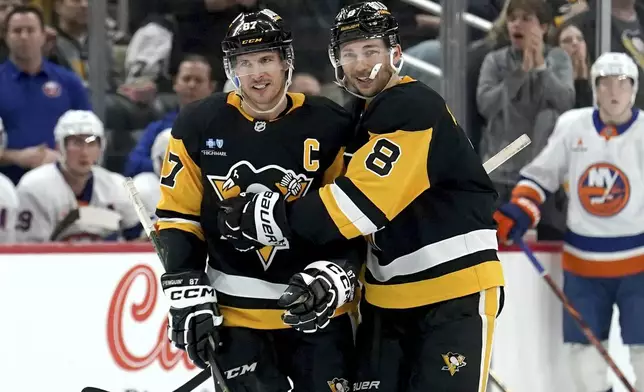 Pittsburgh Penguins' Michael Bunting (8) celebrates with Sidney Crosby (87) after scoring during the second period of an NHL hockey game against the New York Islanders, Sunday, Dec. 29, 2024, in Pittsburgh. (AP Photo/Matt Freed)