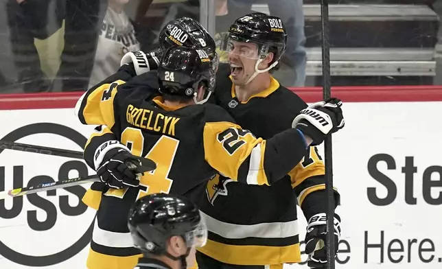 Pittsburgh Penguins' Anthony Beauvillier, right, celebrates with Matt Grzelcyk (24) and Michael Bunting (8) after scoring during the first period of an NHL hockey game against the New York Islanders, Sunday, Dec. 29, 2024, in Pittsburgh. (AP Photo/Matt Freed)