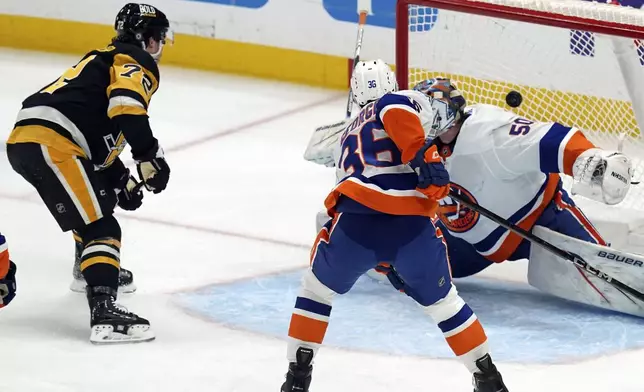 Pittsburgh Penguins' Anthony Beauvillier (72) scores against New York Islanders goaltender Marcus Hogberg (50) as Isaiah George (36) defends during the first period of an NHL hockey game, Sunday, Dec. 29, 2024, in Pittsburgh. (AP Photo/Matt Freed)