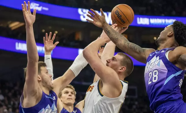 Denver Nuggets center Nikola Jokic, second from right, shoots as Utah Jazz center Walker Kessler, left, forward Lauri Markkanen, second from left, and forward Brice Sensabaugh (28) defend during the first half of an NBA basketball game Monday, Dec. 30, 2024, in Salt Lake City. (AP Photo/Rick Egan)