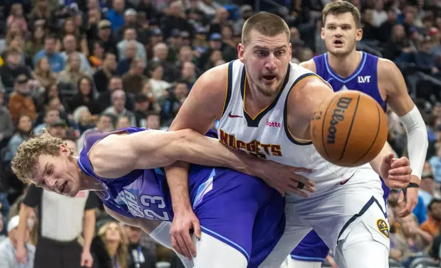 Denver Nuggets center Nikola Jokic, front right, becomes entangled with Utah Jazz forward Lauri Markkanen (23) as Jazz center Walker Kessler, back right, looks on during the first half of an NBA basketball game Monday, Dec. 30, 2024, in Salt Lake City. (AP Photo/Rick Egan)