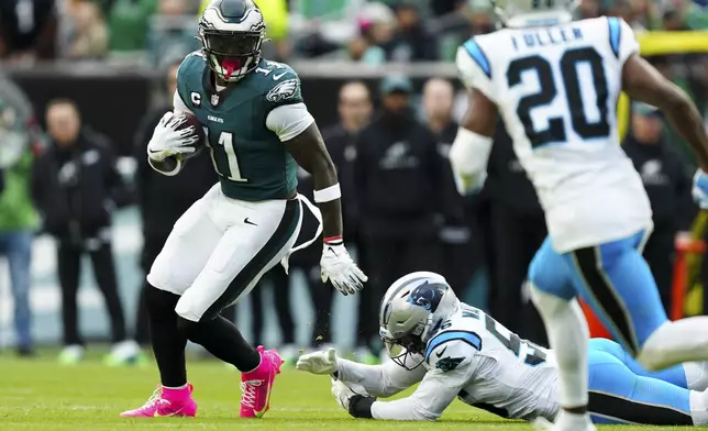 Philadelphia Eagles wide receiver A.J. Brown (11) runs the ball under pressure from Carolina Panthers linebacker Trevin Wallace (56) and Carolina Panthers safety Jordan Fuller (20) during the first half of an NFL football game Sunday, Dec. 8, 2024, in Philadelphia. (AP Photo/Derik Hamilton)