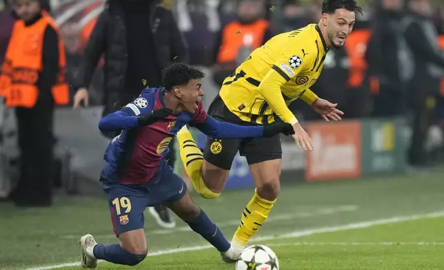 Barcelona's Lamine Yamal fights for the ball against Dortmund's Ramy Bensebaini during the Champions League opening phase soccer match between Borussia Dortmund and FC Barcelona at the Signal-Iduna Park in Dortmund, Germany, Wednesday Dec. 11, 2024. (AP Photo/Martin Meissner)