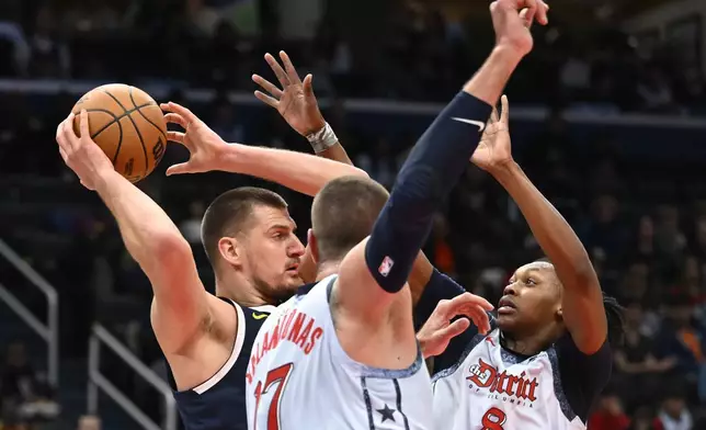 Denver Nuggets center Nikola Jokic, left, is defended by Washington Wizards center Jonas Valanciunas, center, and guard Carlton Carrington (8) during the second half of an NBA basketball game Saturday, Dec. 7, 2024, in Washington. (AP Photo/John McDonnell)