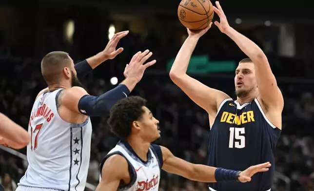 Denver Nuggets center Nikola Jokic (15) loooks to score a basket over Washington Wizards center Jonas Valanciunas, left, and Wizards guard Jordan Poole, center, during the second half of an NBA basketball game Saturday, Dec. 7, 2024, in Washington. (AP Photo/John McDonnell)