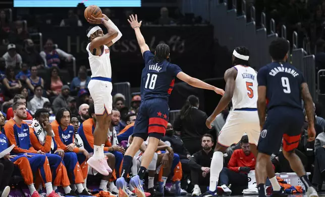 New York Knicks guard Miles McBride, front left, attempts a 3-point basket during the first half of an NBA basketball game against the Washington Wizards, Saturday, Dec. 28, 2024, in Washington. (AP Photo/Terrance Williams)